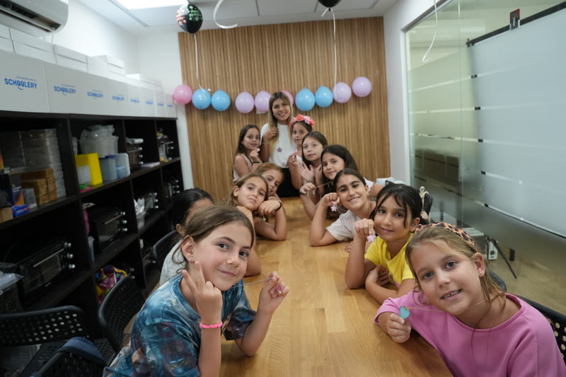 ילדות מציגות תכשיטים שיצרו בסדנת יום הולדת של סקולרי